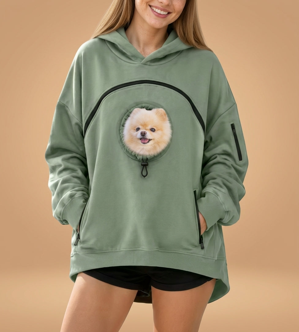 Sudadera con bolsillo para mascota en color verde salvia, con un pomerania asomando por la ventana del bolsillo
